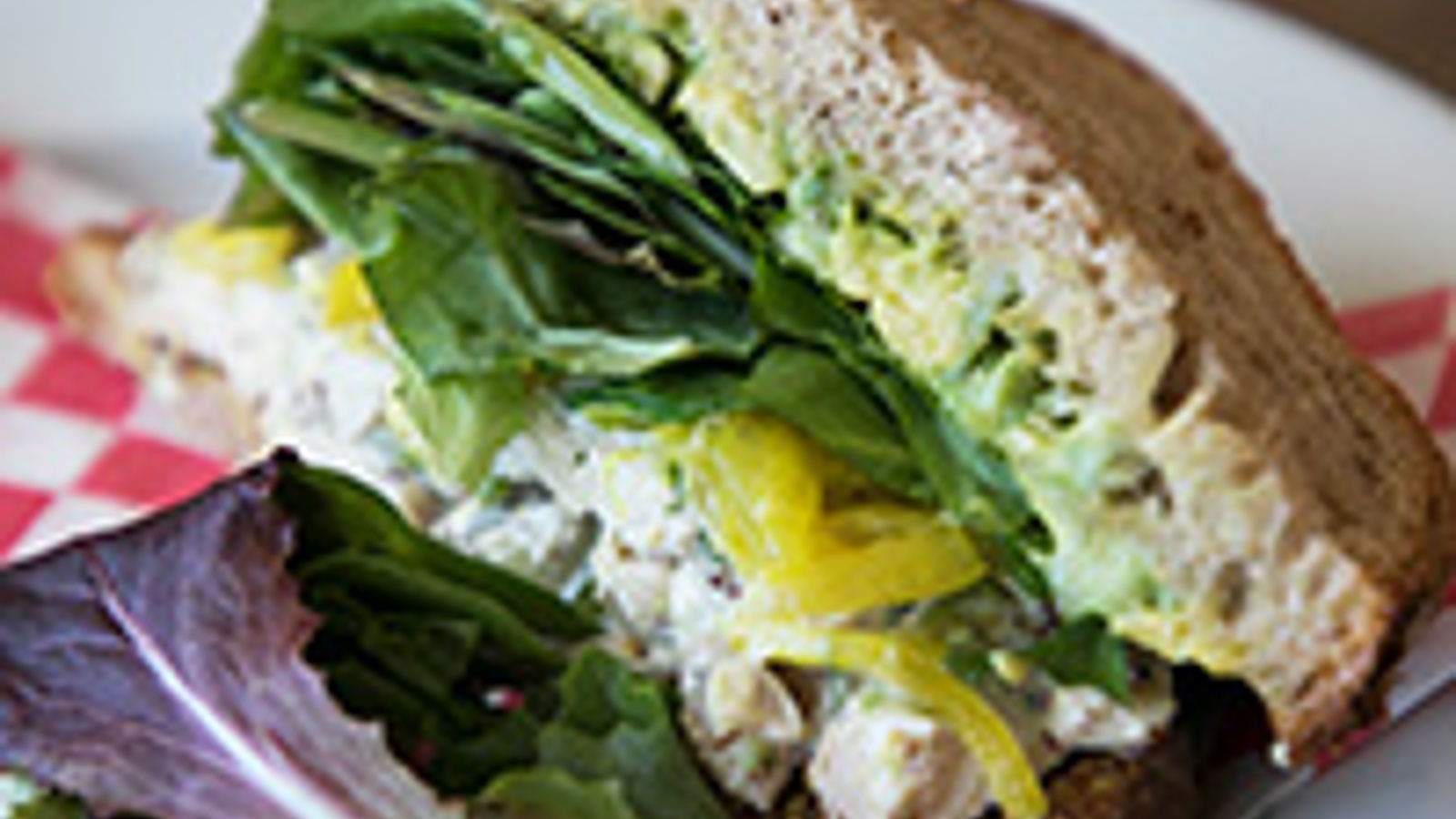 Roasted chicken salad sandwich with avocado, lettuces and pickled onions